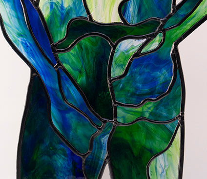 Close Up of the detailed Leading: 

A luxurious stained glass artwork depicts a human figure from the back in serene shades of blue and green. The figure stands confidently on a wooden base, hands resting on the hips. This semi-transparent piece, perfect for collectors, allows light to pass through beautifully. An exceptional example of skilled craftsmanship- this artwork was cut from a single sheet of glass.