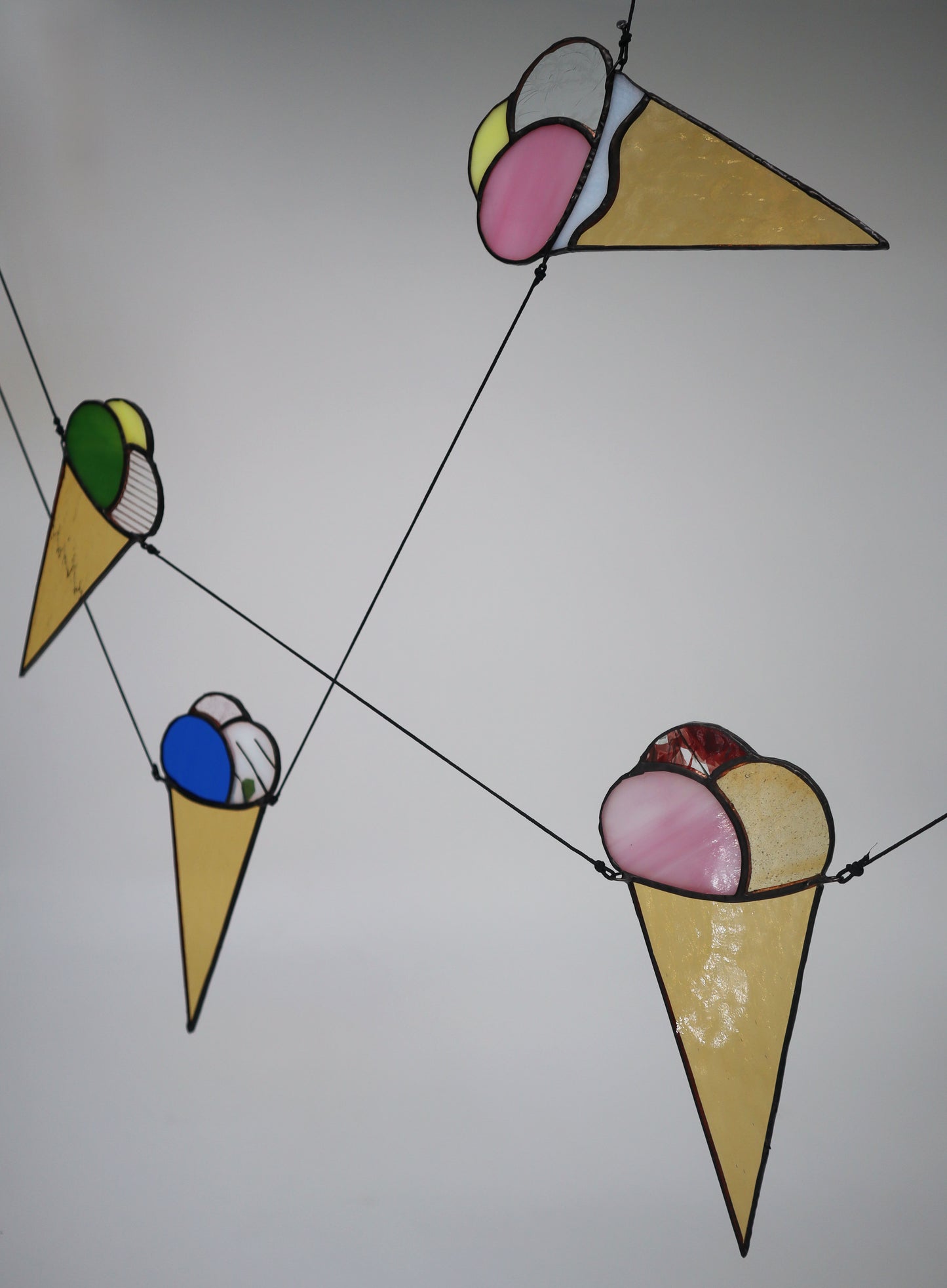 The LF Kaleidoscope Ice Cream Bunting, made of stained glass, showcases delightful ice cream cones and dipped ‘sugar cones’ in three scoops combinations. Choose your favourite colourful flavours. This unique bunting features a string of 5 cone designs each with a unique one-off flavour combo in clear, red, orange, green, blue, stripped, purple, pink, yellow and textured colours. Choose your family favourites. 