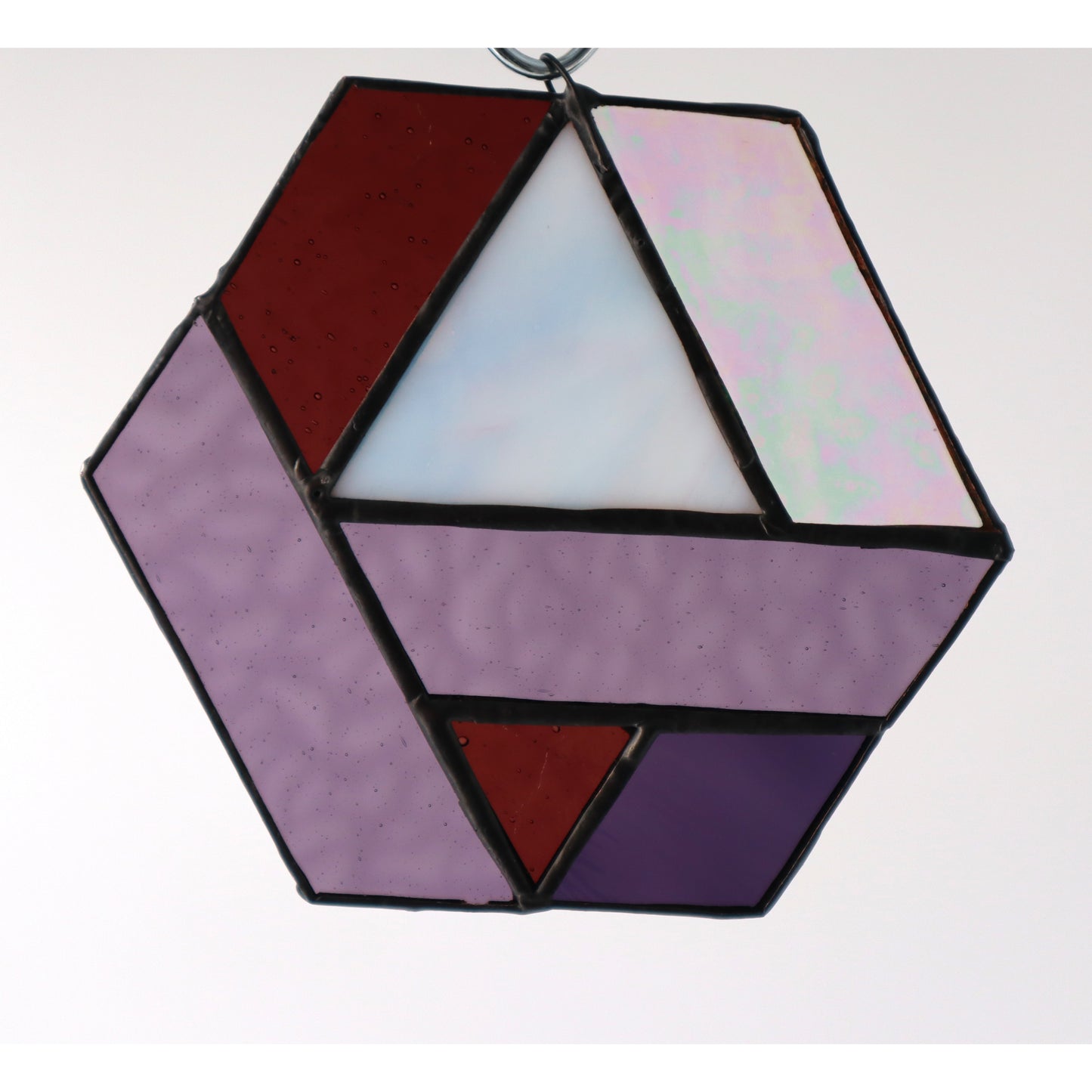 Introducing the "Hexagons, Purple" by LF Kaleidoscope: a stunning geometric-inspired stained glass ornament crafted from vintage glass offcuts. This hexagonal piece showcases a mix of textured lavender, iridescent, and solid shades of purple that hang beautifully against any plain background.