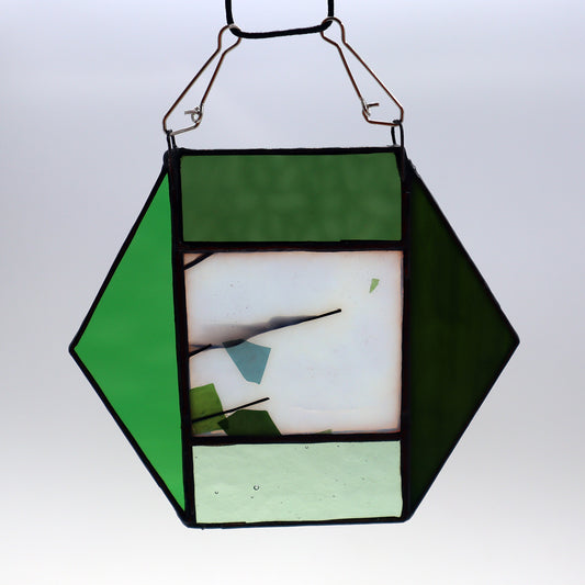 The "Hexagon, Green" ornament by LF Kaleidoscope features a geometric design made from vintage glass with an array of green and clear panels, elegantly hanging against a light background.