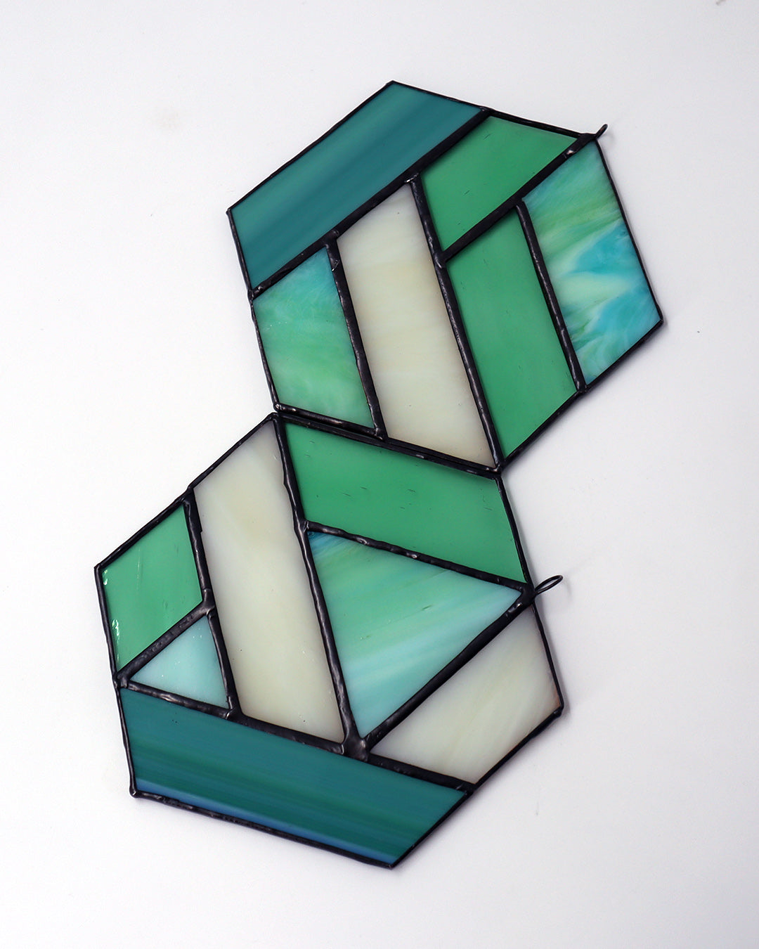 The "Hexagon, Green" ornament by LF Kaleidoscope features a geometric design made from vintage glass with an array of green and clear panels, elegantly hanging against a light background.