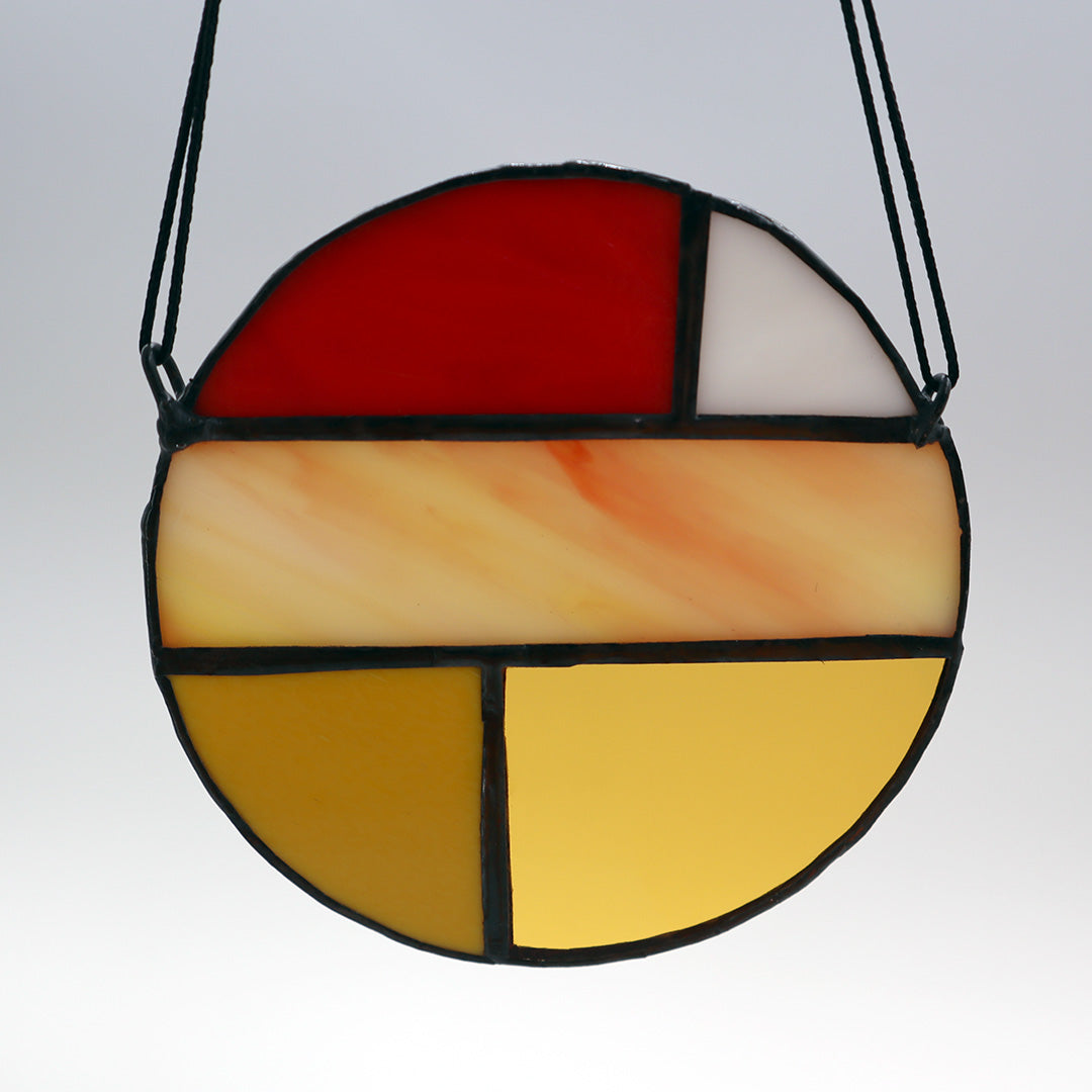 Featuring four distinct pieces, these stained glass circles by LF Kaleidoscope exhibit geometric designs in shades of red, yellow, orange, and white. Each circle is elegantly framed in black and equipped with strings for effortless hanging. They are artistically displayed on a light surface to enhance their vibrant colors.