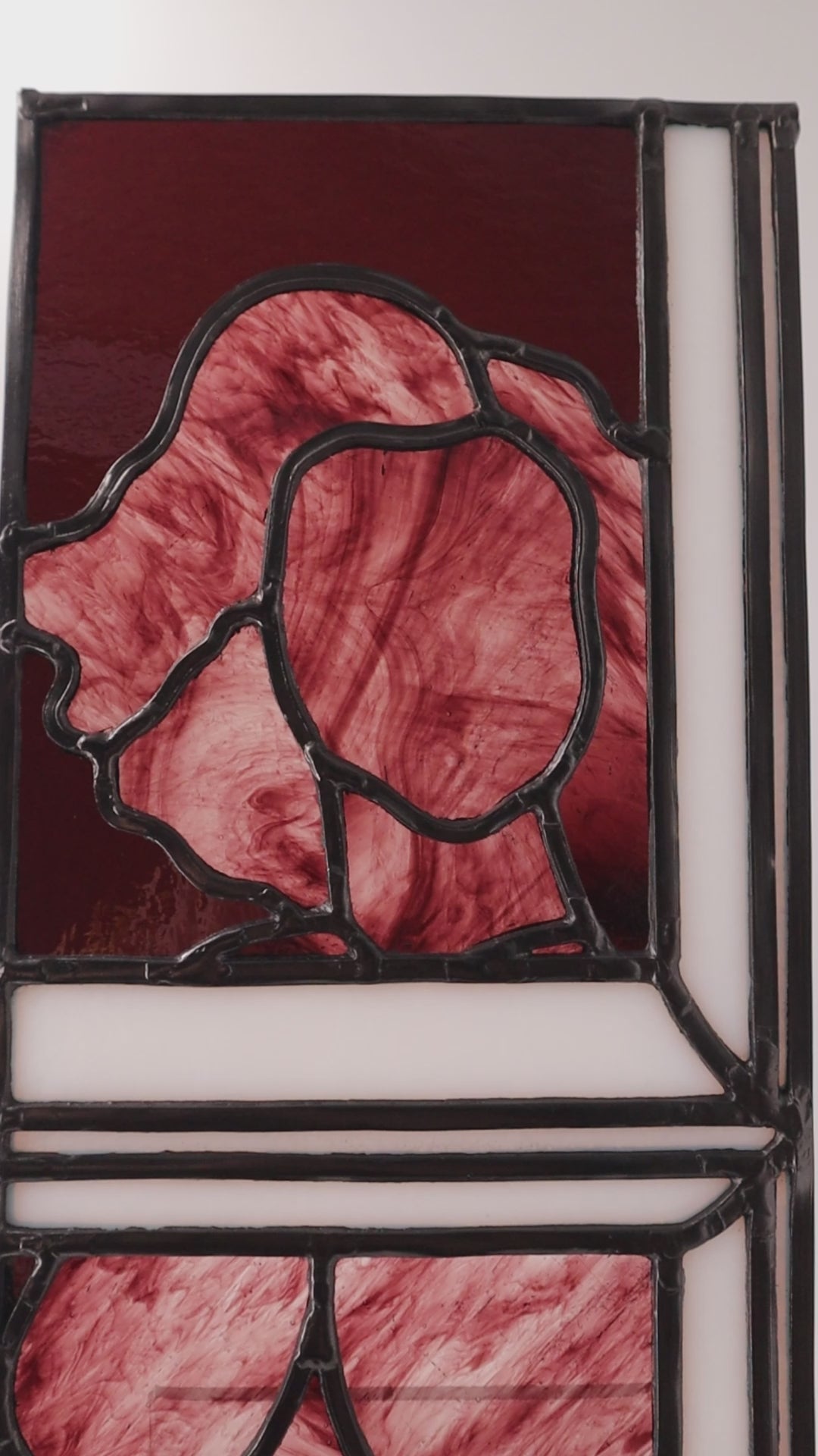 Video showing: 

Alfreda, another example of LF Kaleidoscope’s Stained Glass Portraits. This stunning artwork captures the life model reflected in a bedroom window. Alfreda’s portrait showcases her flowing hair, and beautiful torso shapes rendered in deep red, luxuriant purples with the black lead lines creating structure and definition against the white glass window frame. Alfreda is staring through the window at you, and would look excellent in any house or gallery.