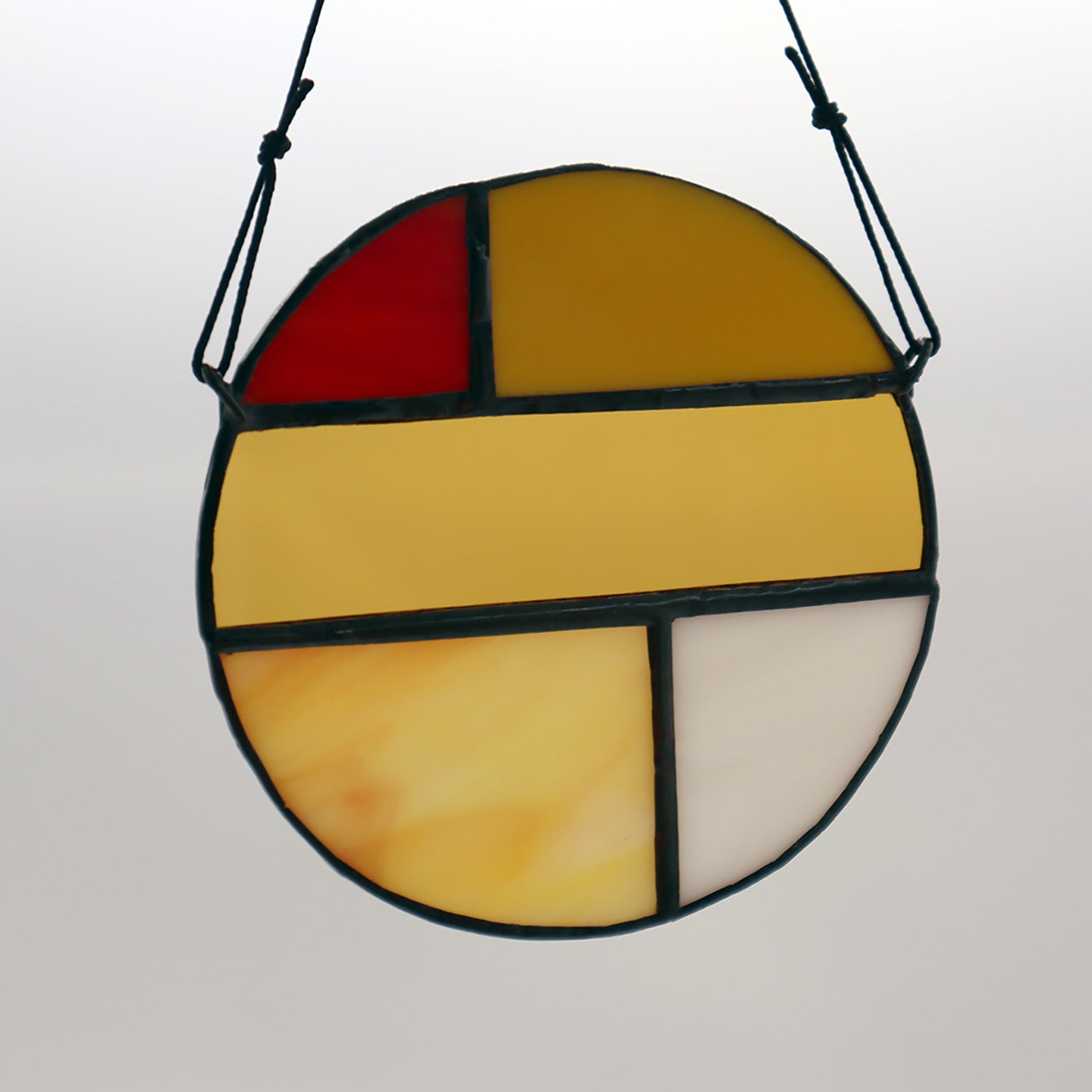 Featuring four distinct pieces, these stained glass circles by LF Kaleidoscope exhibit geometric designs in shades of red, yellow, orange, and white. Each circle is elegantly framed in black and equipped with strings for effortless hanging. They are artistically displayed on a light surface to enhance their vibrant colors.